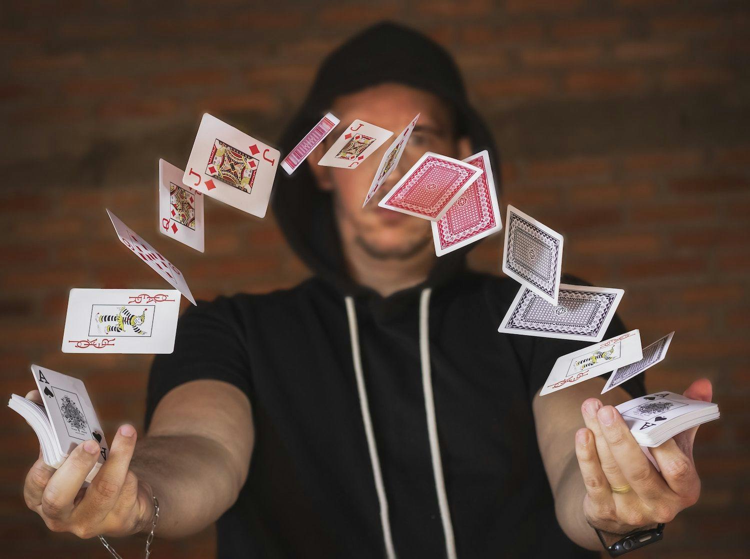 Image shows man throwing a deck of cards. 