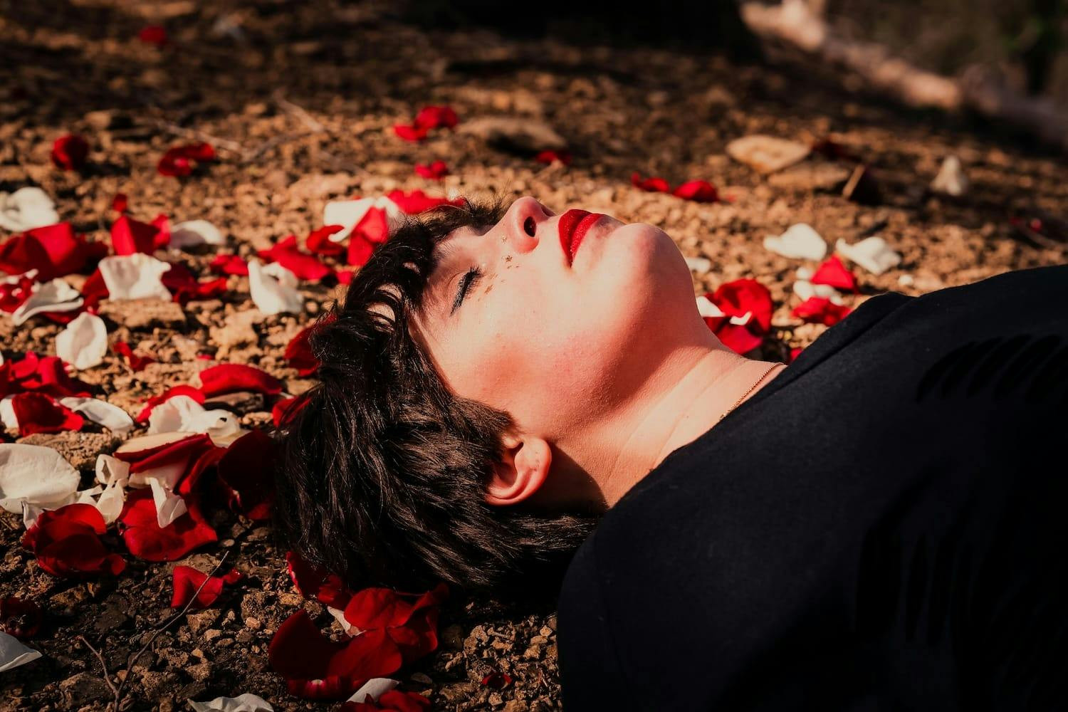 Woman lying down surrounded by rose petals