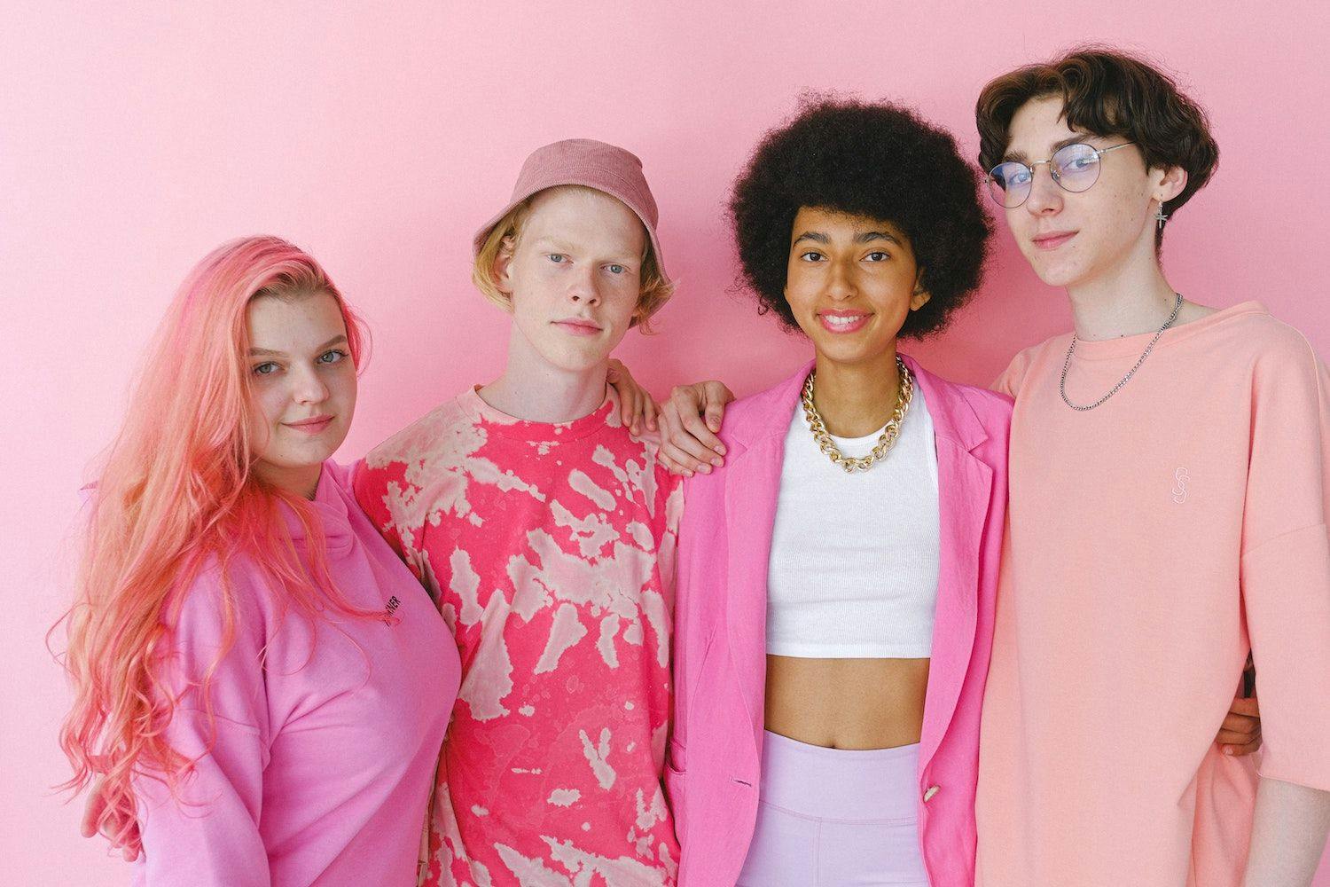 Four teens stand together, all wearing pink