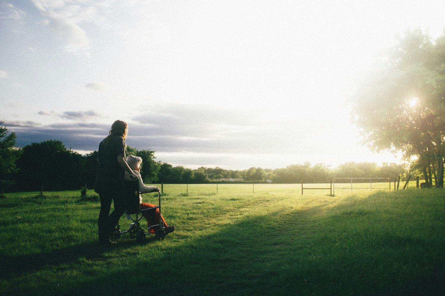Image shows a carer and person looking out across a field. 