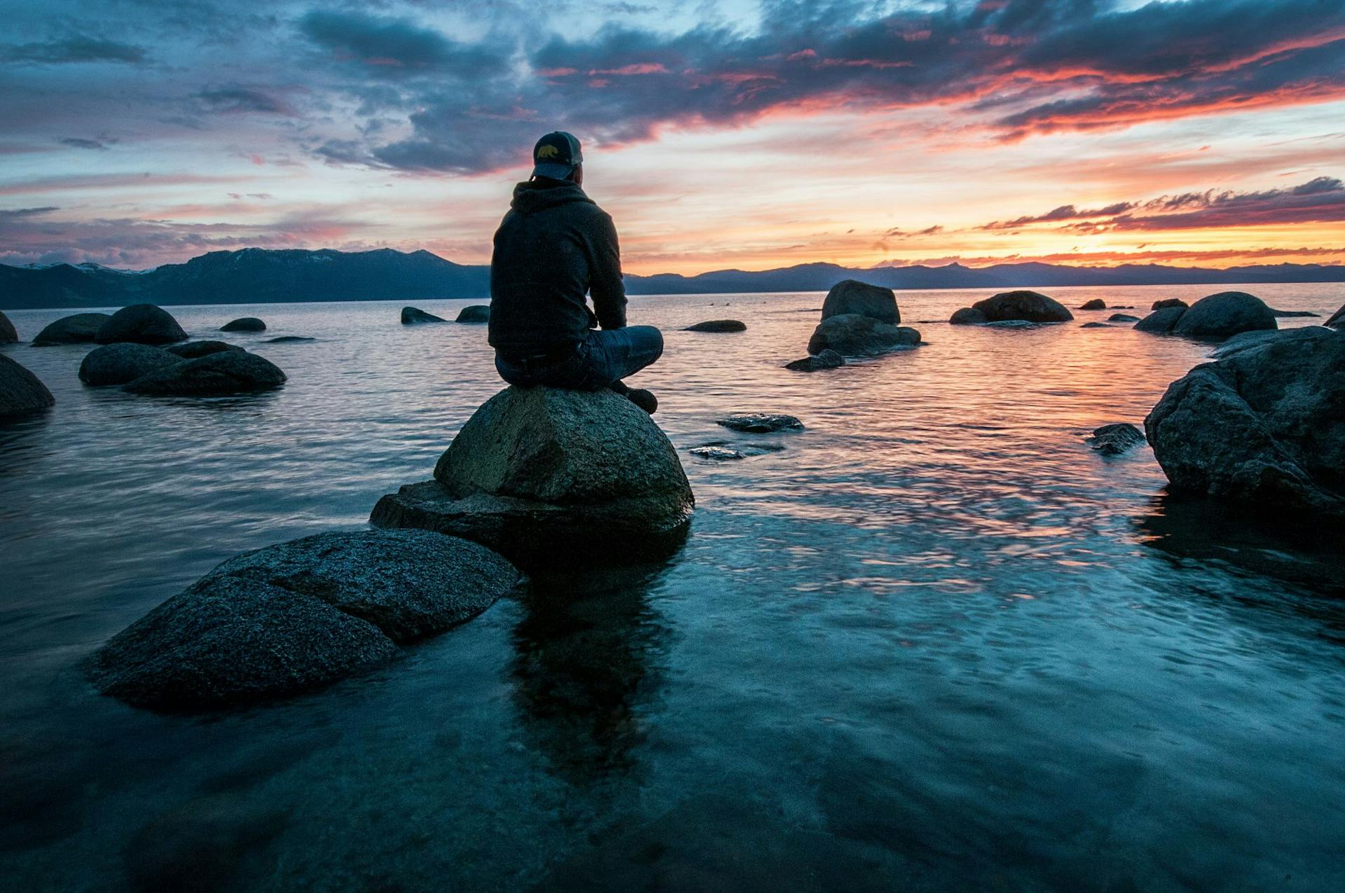 Man sitting on rock at sunset