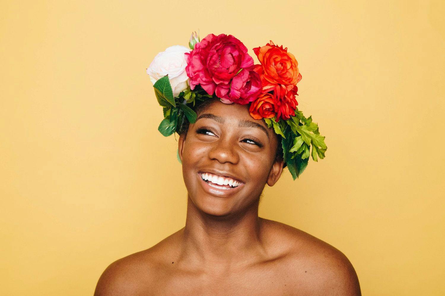 Person wearing a flower crown stood in front of a yellow background. 