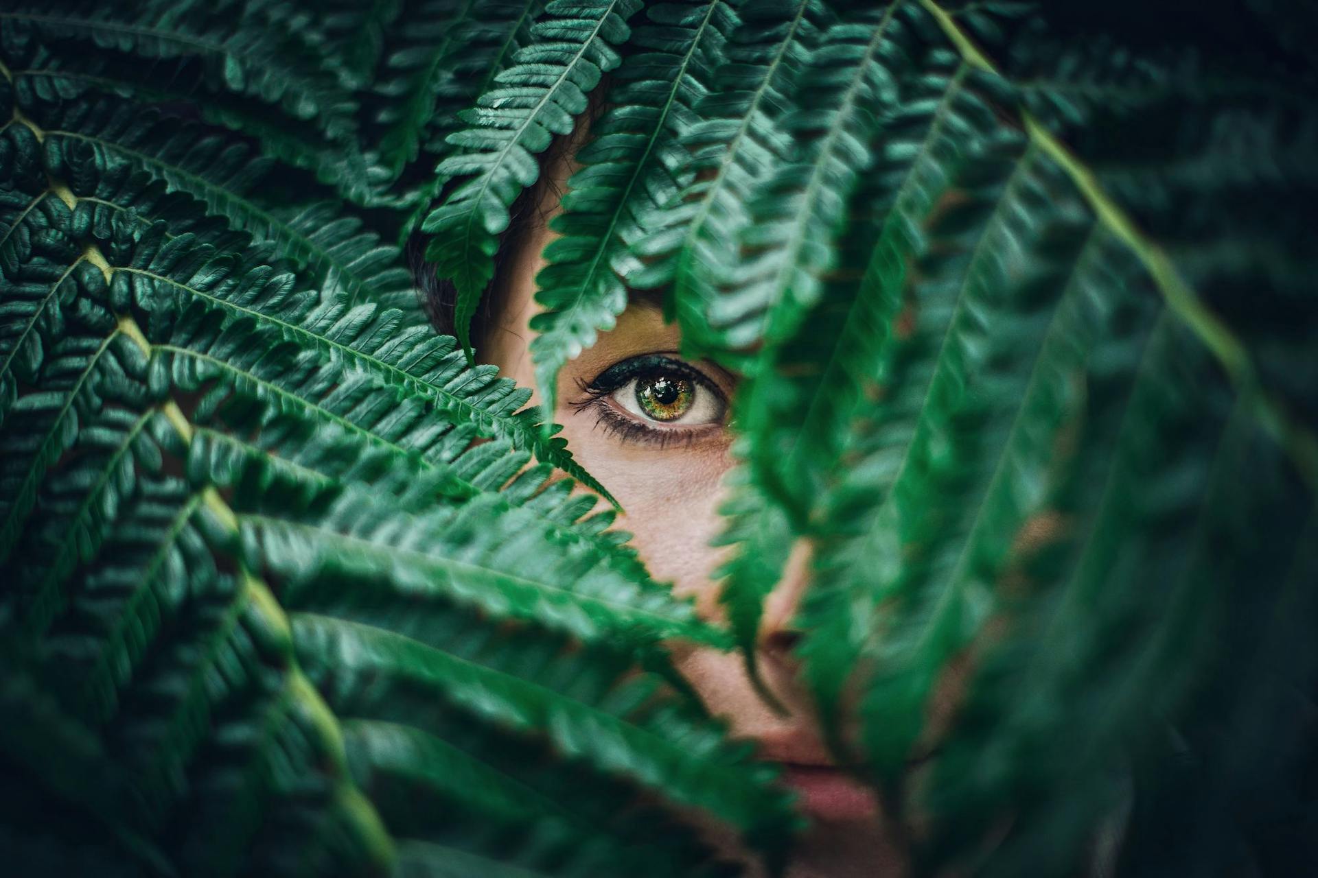 woman hiding behind green plant