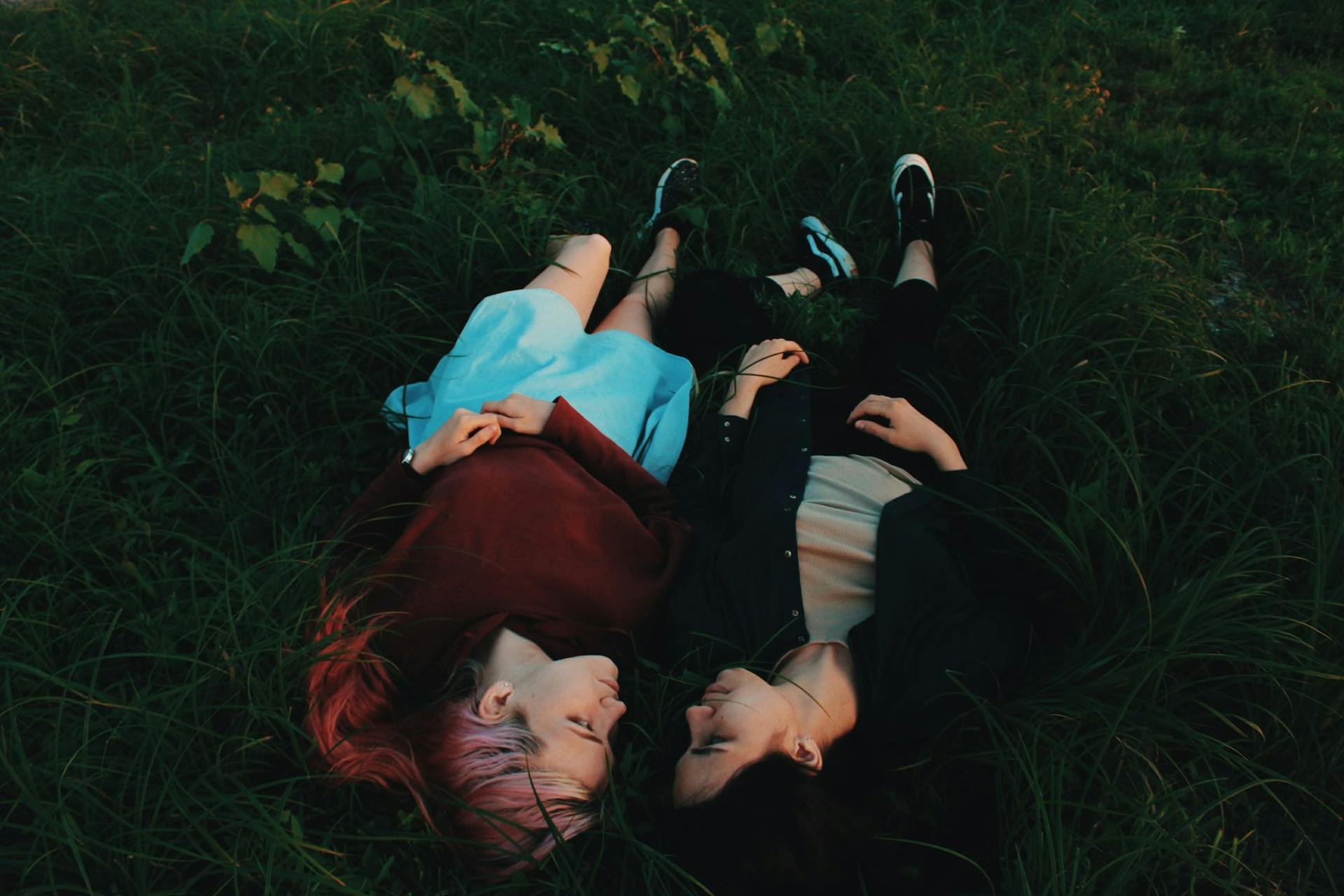 Two women look at each other while laying in the grass