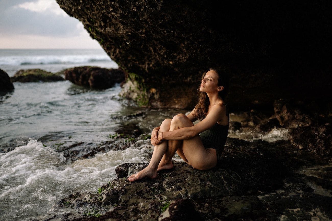 Woman sat on rocks by the sea