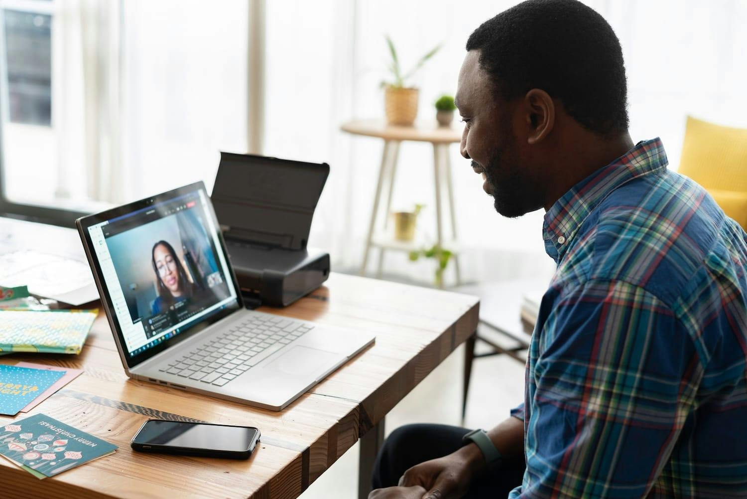 Image shows a man working from home having a video call with a colleague. 