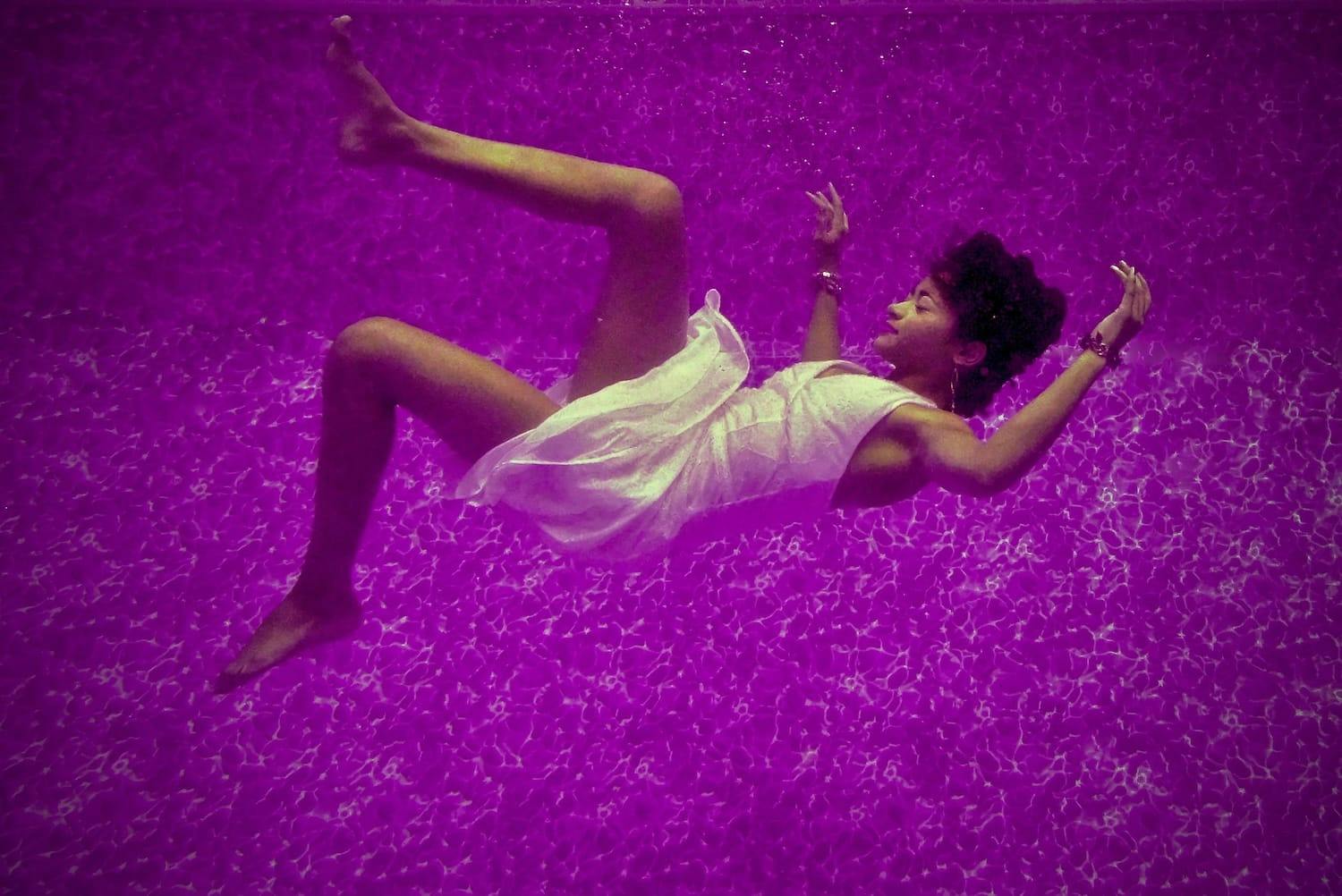 Person shows a woman falling in her sleep with purple background.