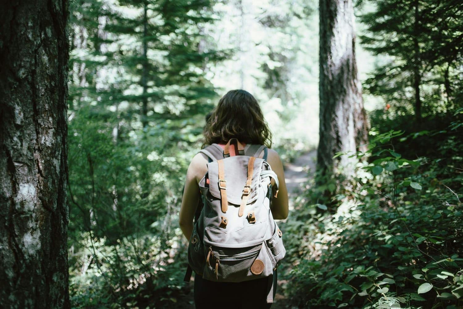 Image shows a woman walking through a forest.