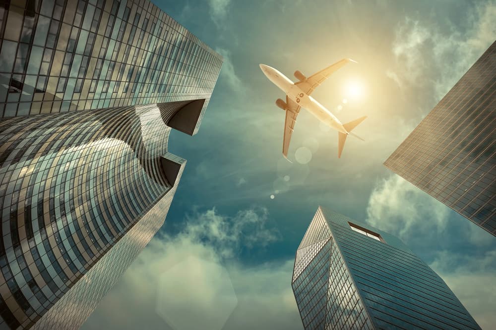 This is a photo of a plane flying over mirrored glass buildings