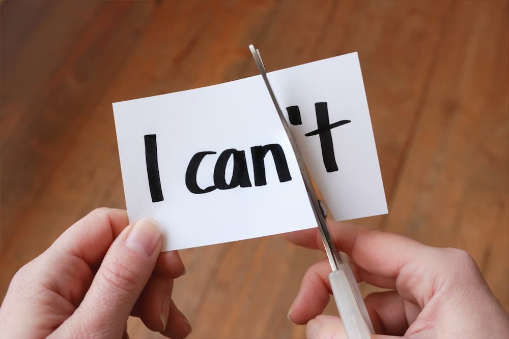 This is a photo of someone cutting the word 'I can't' so it reads 'I can'