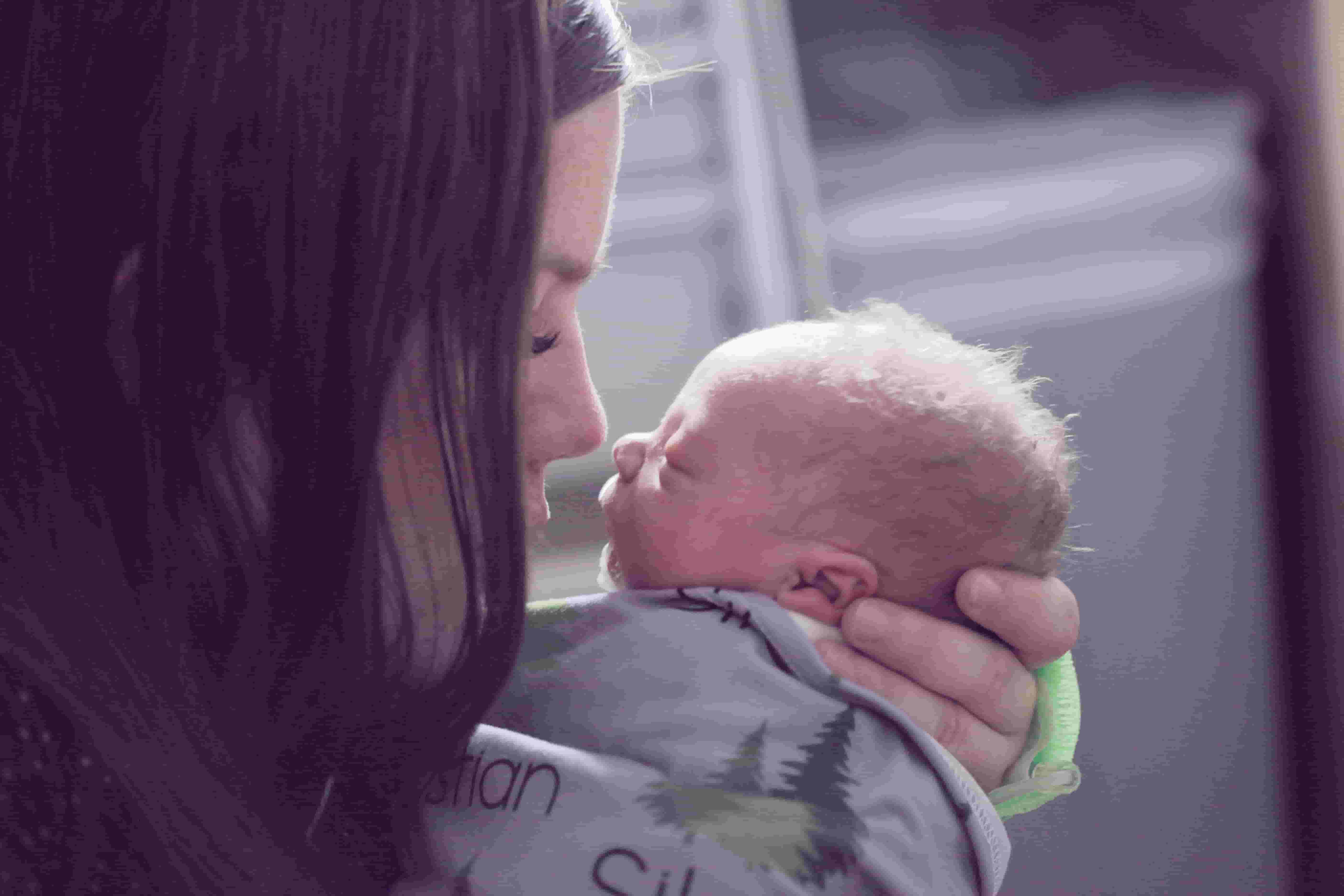 A woman kisses a newborn baby