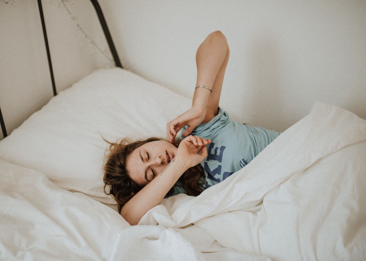 Person stretching arms in bed.