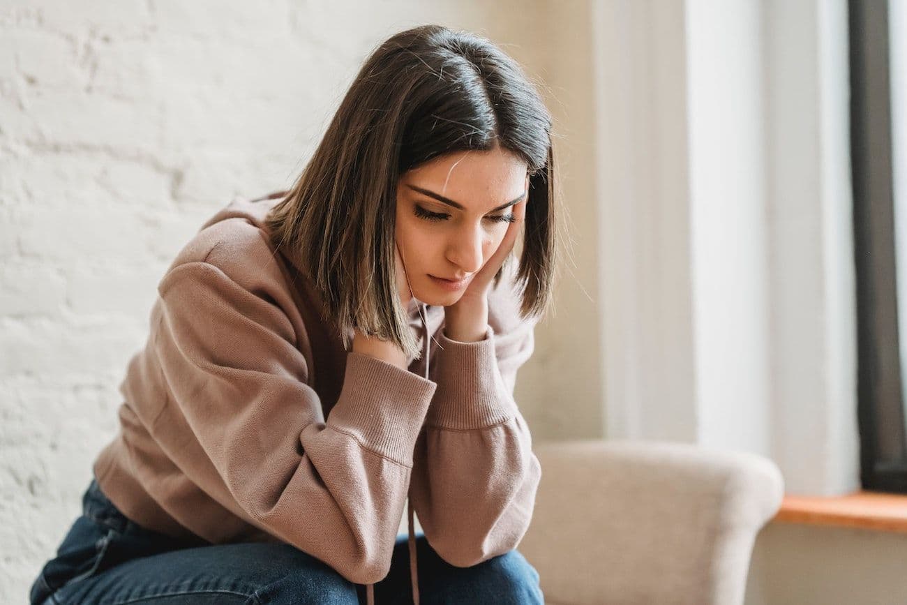 Woman resting head on hands, looking worried.