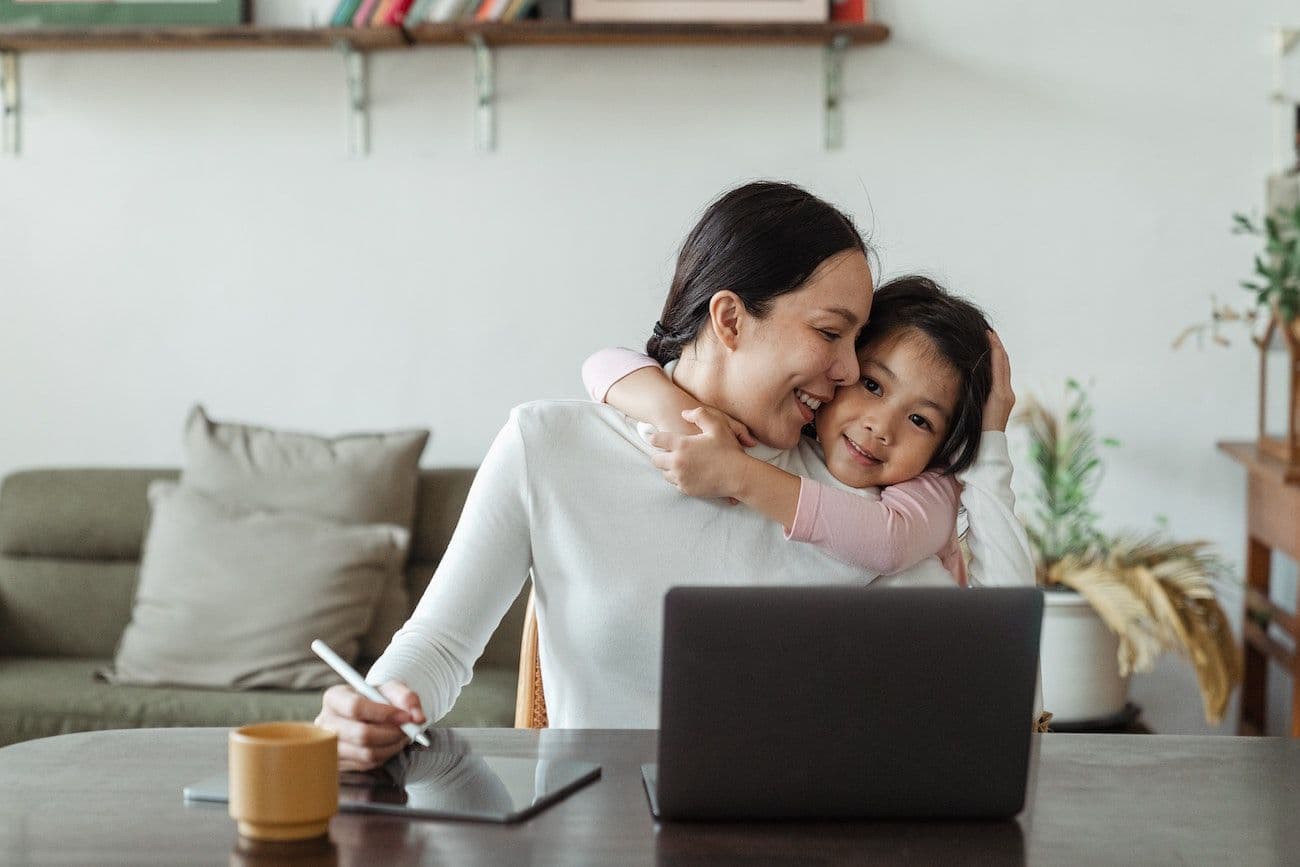 Mother hugging child in front of computer