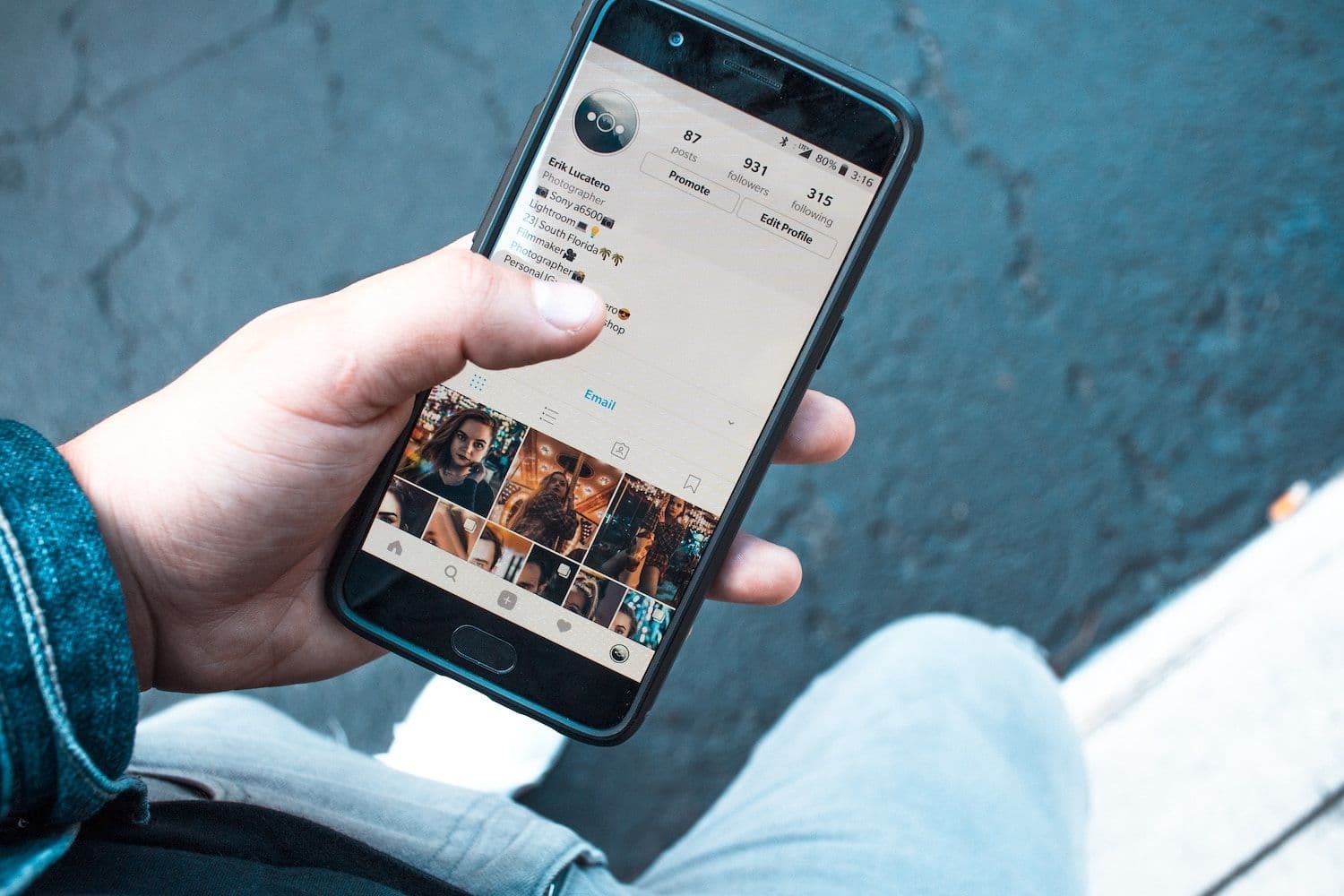 Image shows a persons hand holding a phone, scrolling through social media.