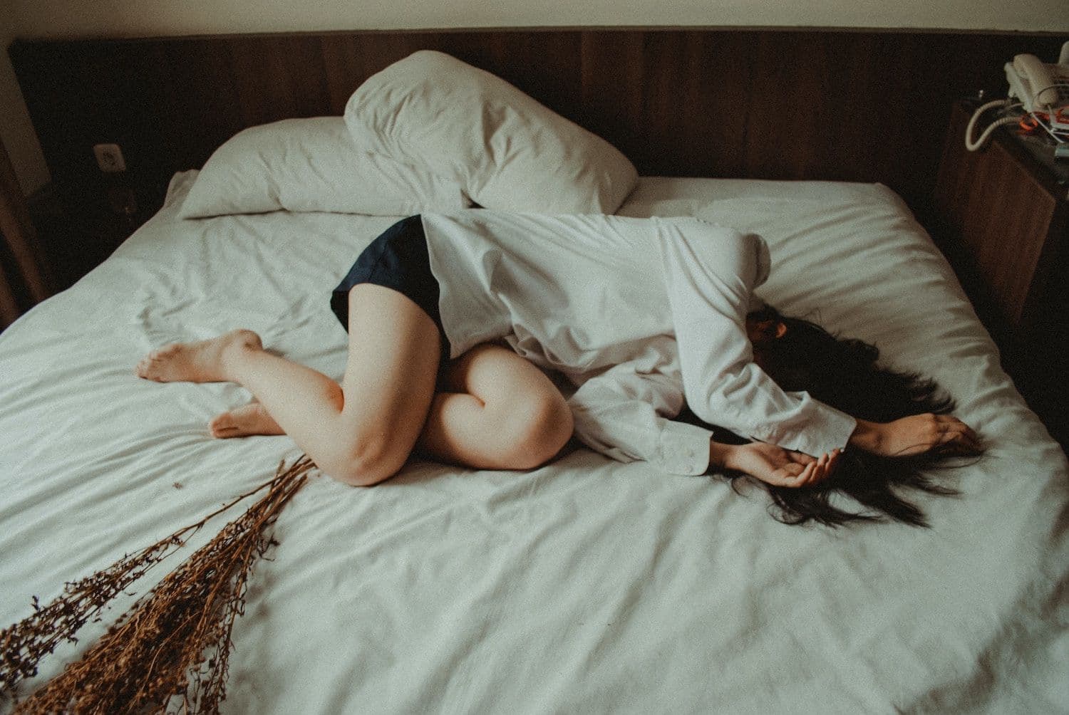Image shows woman curled up on a bed.