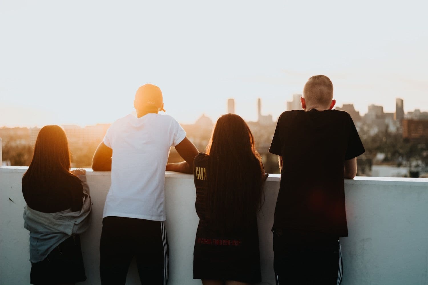 Four friends with their back to the camera looking out at the view of a city.