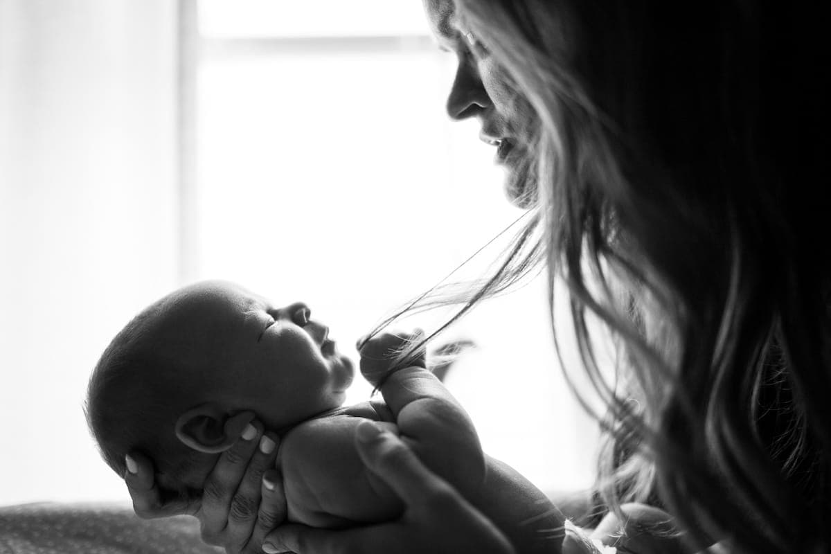 Black and white image showing a woman holding a baby.