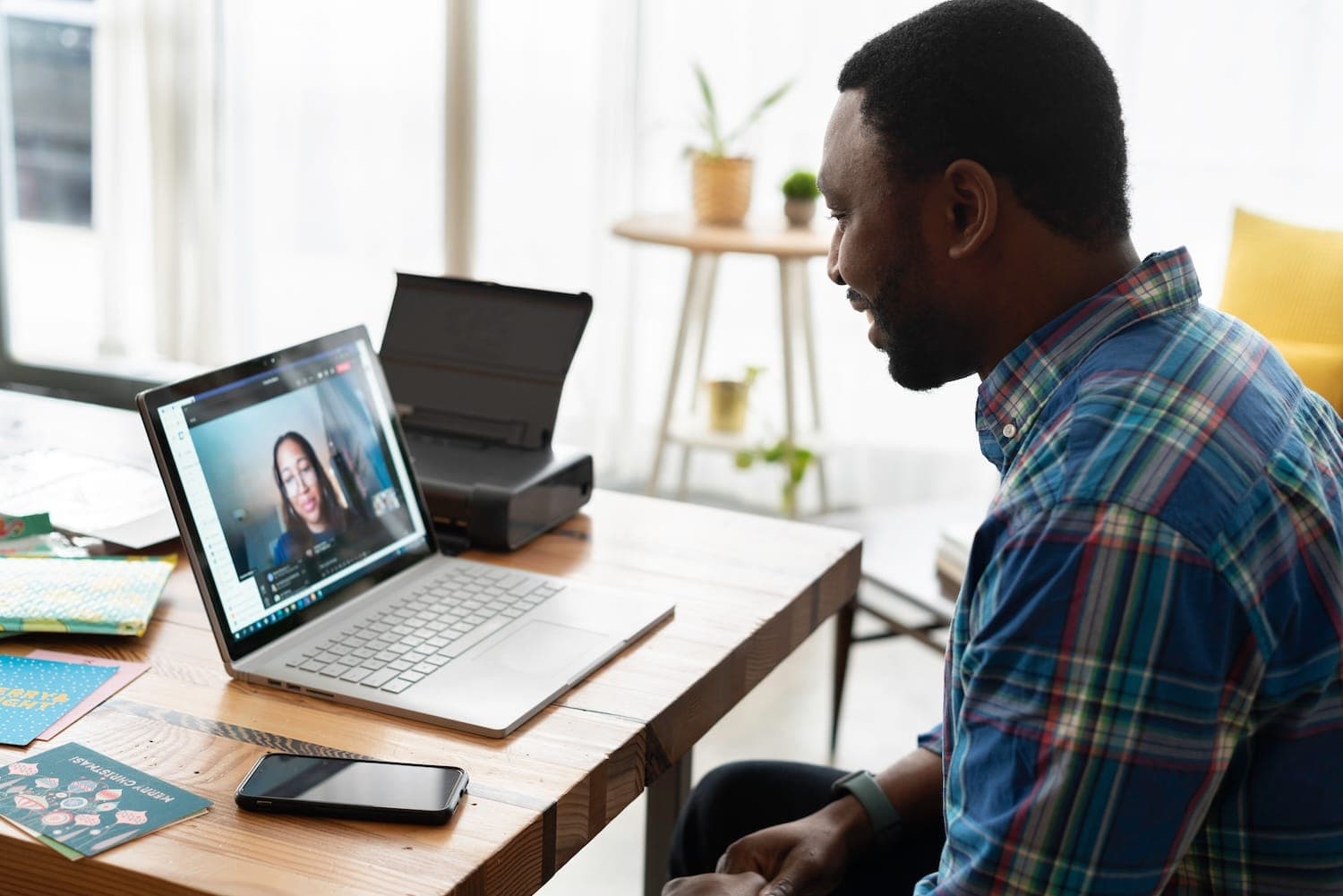 Image shows a man working from home having a video call with a colleague.