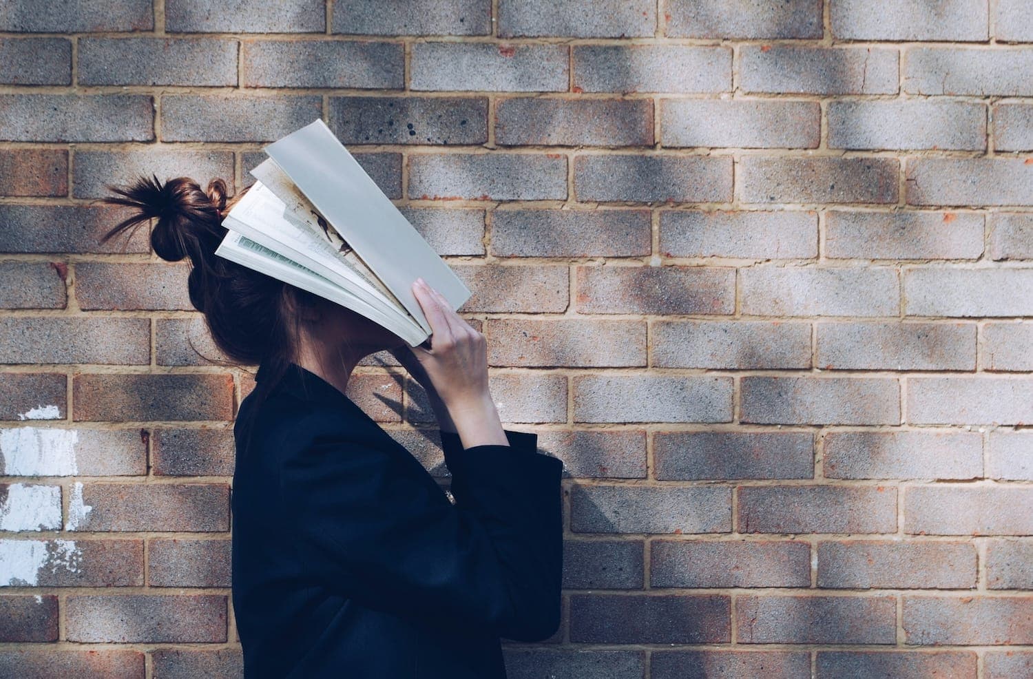 Image shows a person with her head buried in a book.