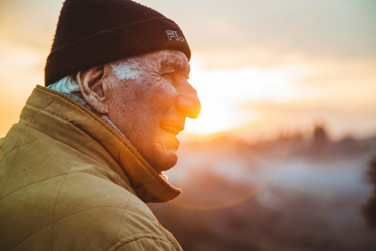 Image shows older man with sunset behind him.