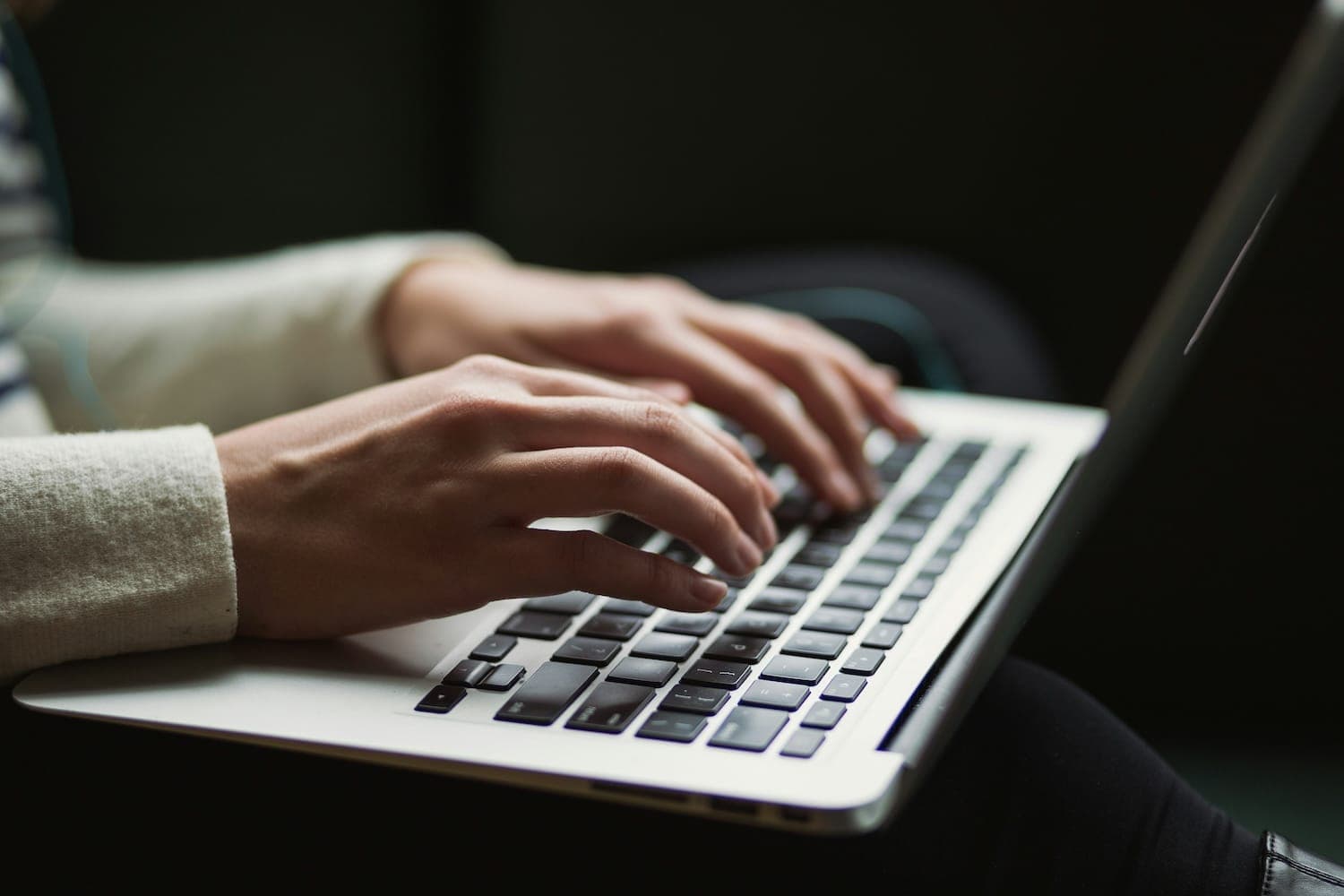 Image shows person typing on a laptop.
